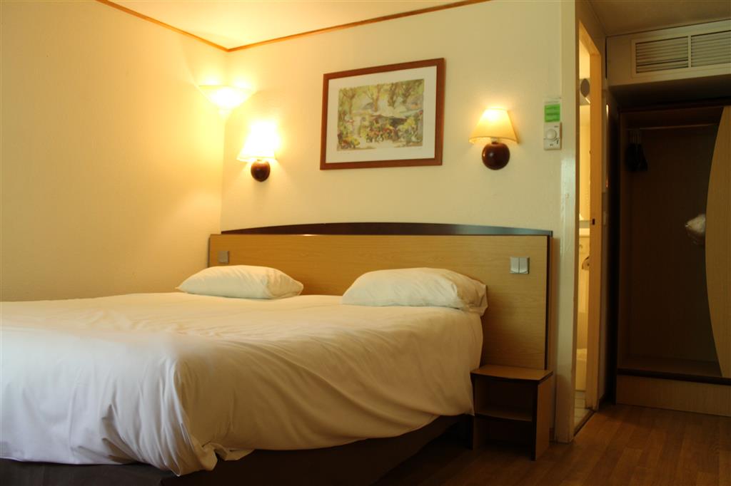Chambre avec grand lit, tête de lit en bois et accès à la salle de bain